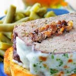 a slice of french onion meatloaf plated with green beans and a slice of garlic bread