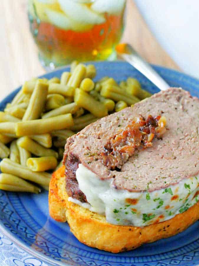 a slice of french onion meatloaf plated with garlic bread and green beans