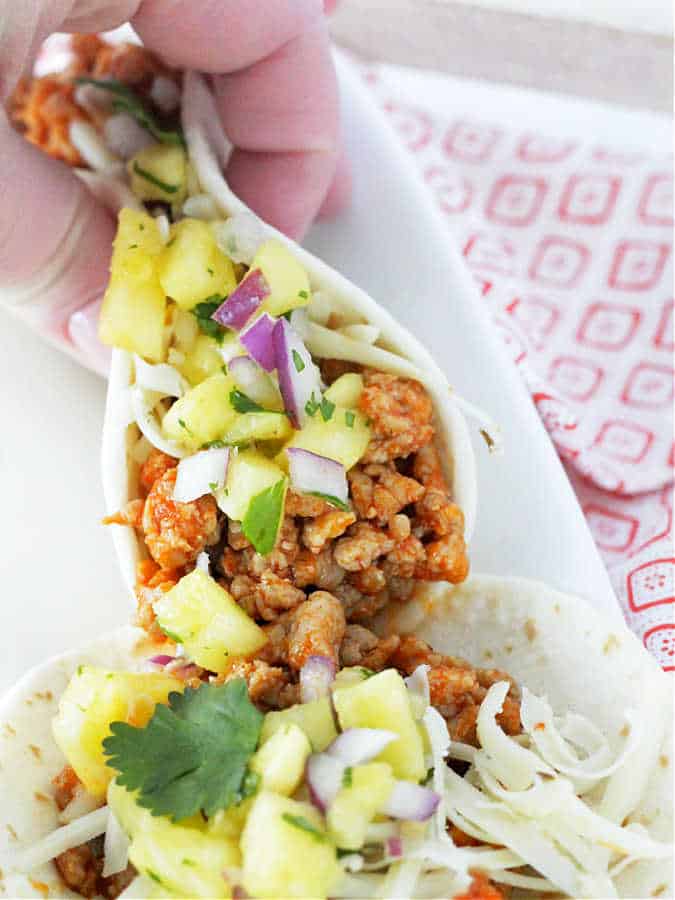 ready to take a bite of a ground pork taco with pineapple salsa