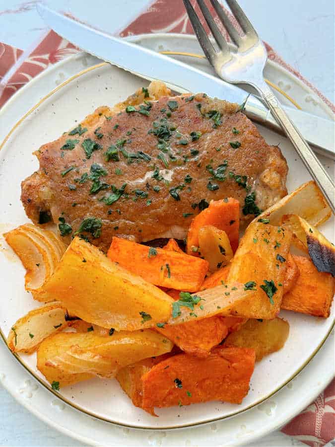 plated pork chops and applesauce with a side of potatoes and onion