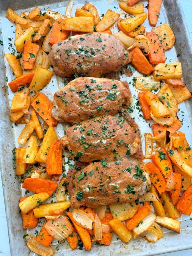 four boneless pork chops glazed with applesauce and surrounded by roasted potatoes and onions