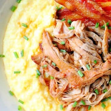 slow cooker pork tenderloin plated with cheese grits and a side of bacon