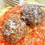 two air fryer meatballs atop a pile of spaghetti and red sauce