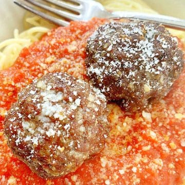 two air fryer meatballs atop a pile of spaghetti and red sauce