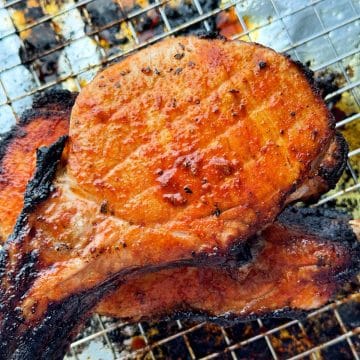 broiled pork chops just out of the oven, resting on the cooling rack