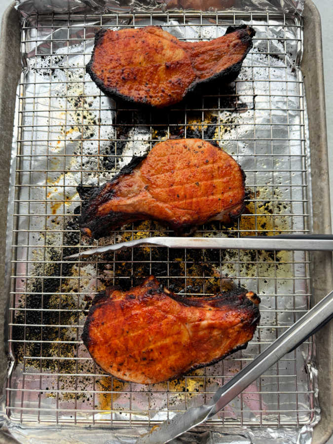 three broiled pork chops on a sheet pan