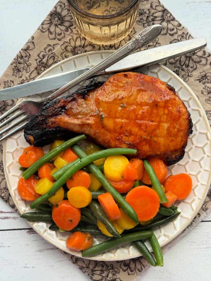 plated broiled pork chop with glazed carrots and fresh green beans