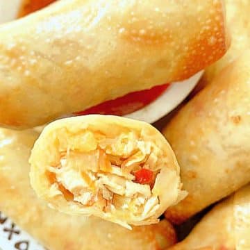 air fryer egg rolls on a plate with dipping sauce. One is cut in half to show the filling inside.