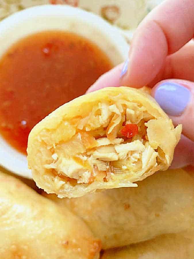 dipping an egg roll into a small bowl of sweet chili sauce