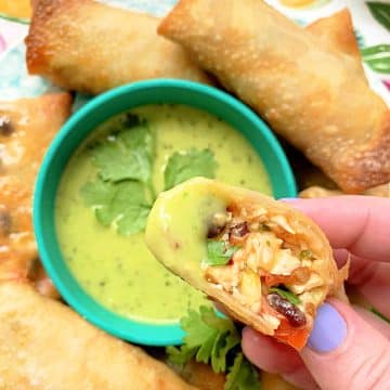 dipping a southwest air fryer egg roll into creamy avocado dipping sauce