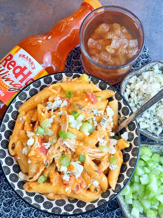 a bowl of one pot buffalo chicken pasta, garnished with chopped celery and crumbled blue cheese