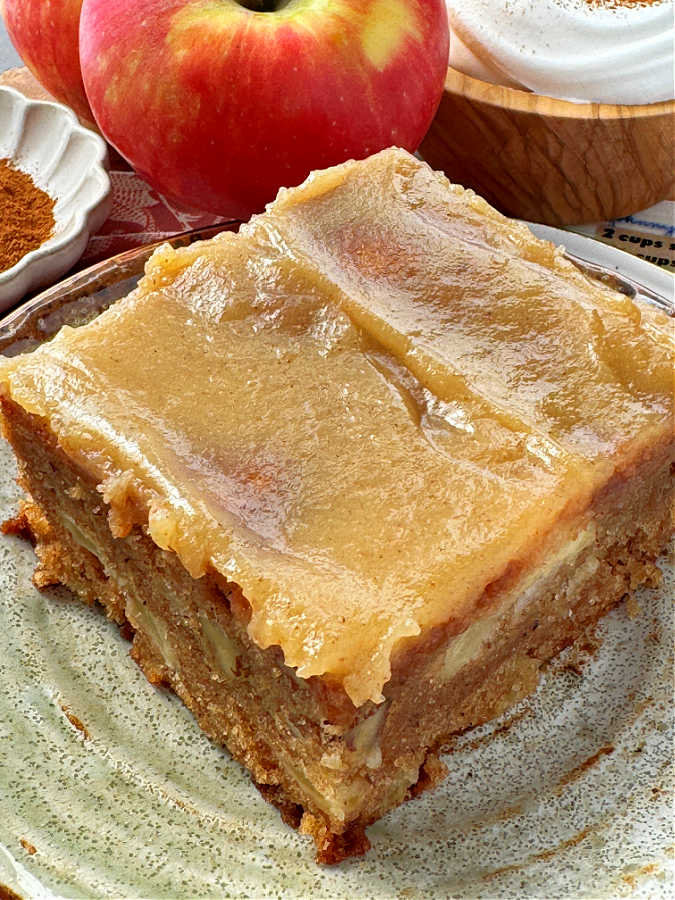 slice of apple cake plated and topped with caramel glaze
