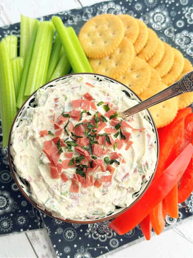 dried beef dip in a bowl plated with Ritz crackers, celery sticks and sliced red bell pepper
