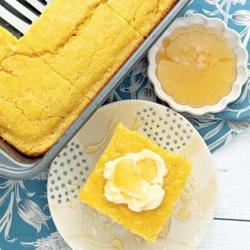 a slice of sweet honey cornbread from the pan, topped with butter and drizzled with honey