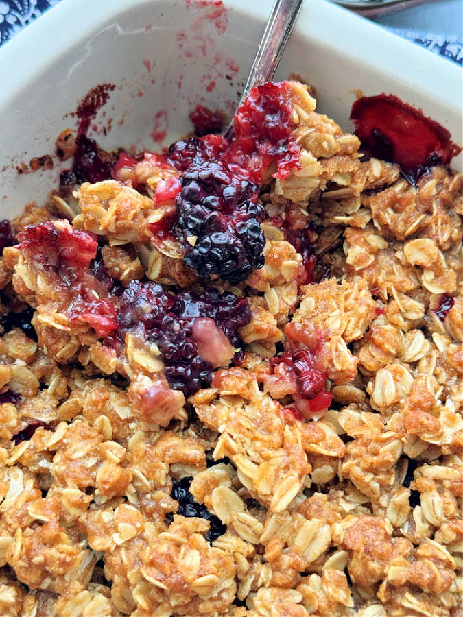 a closeup of a spoonful of blackberry crisp, ready to be served