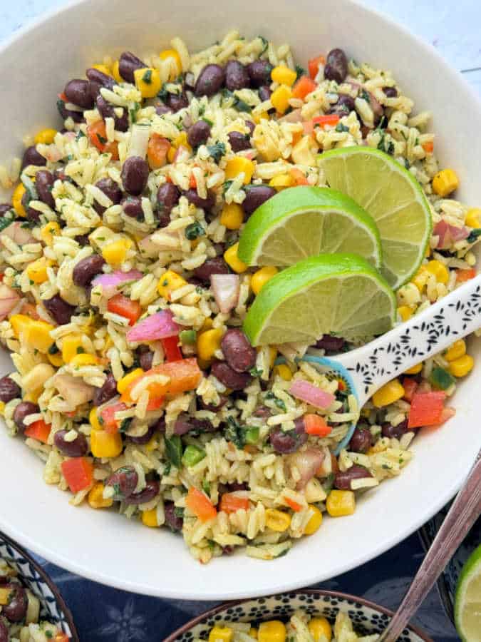 a large bowl of bean and rice salad garnished with fresh lime slices