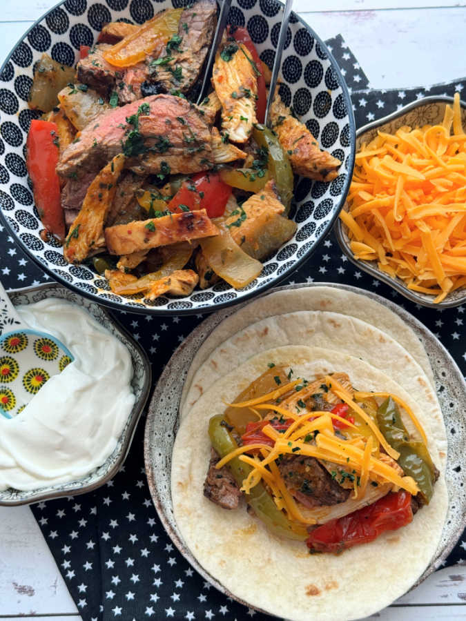 plated air fryer fajitas ready to serve with sides of cheddar cheese and sour cream