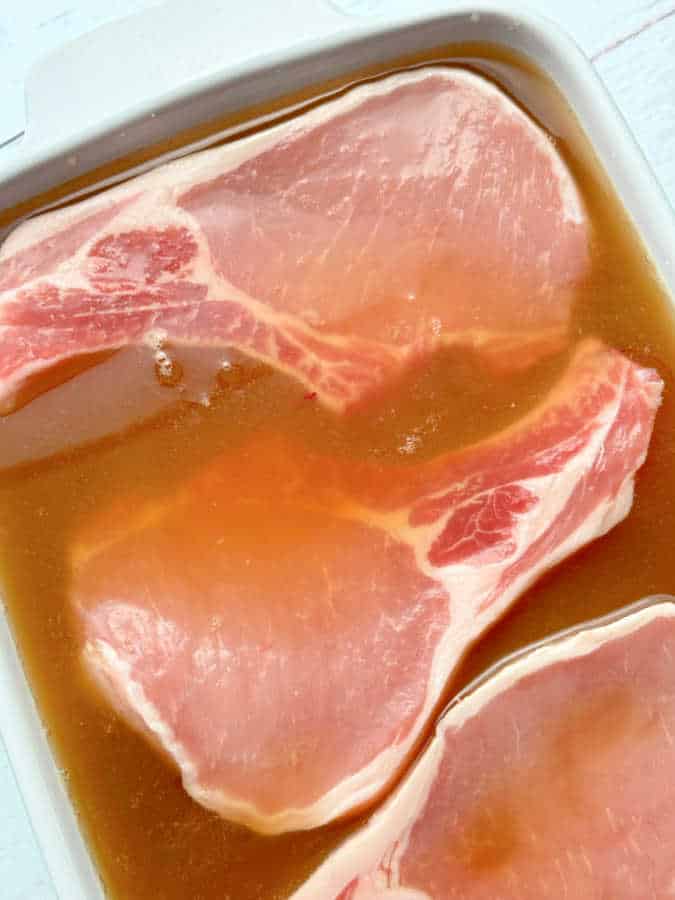 pork chops in a dish being brined