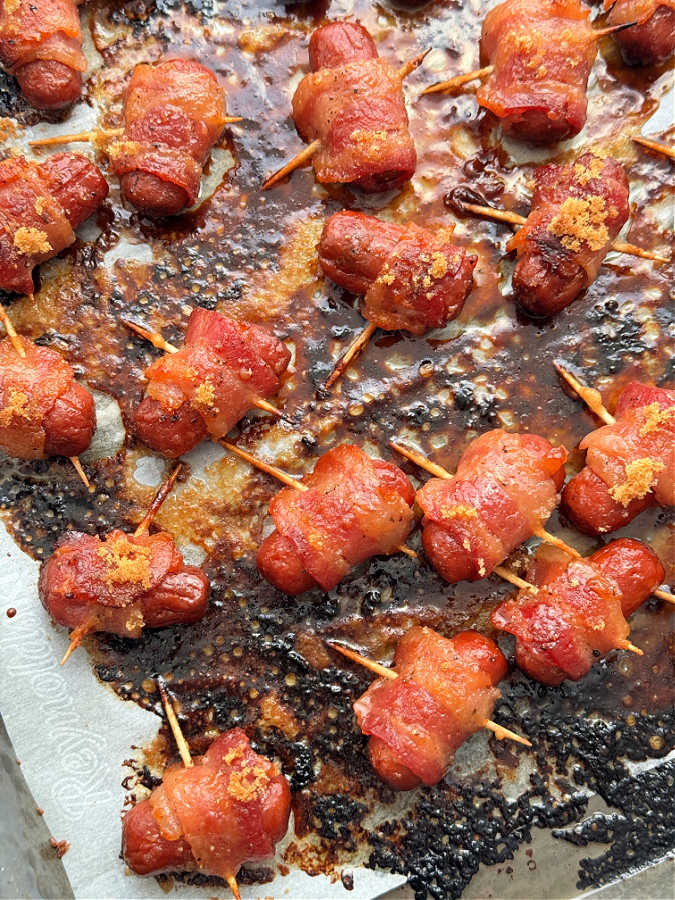 bacon wrapped smokies freshly baked on a sheet pan lined with parchment paper