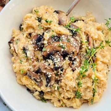 creamy chicken mushroom risotto plated and garnished with fresh thyme