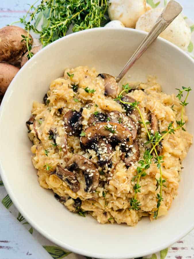 chicken mushroom risotto plated and garnished with fresh thyme and Parmesan cheese