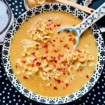 a bowl of peanut butter ramen noodles garnished with red pepper flakes