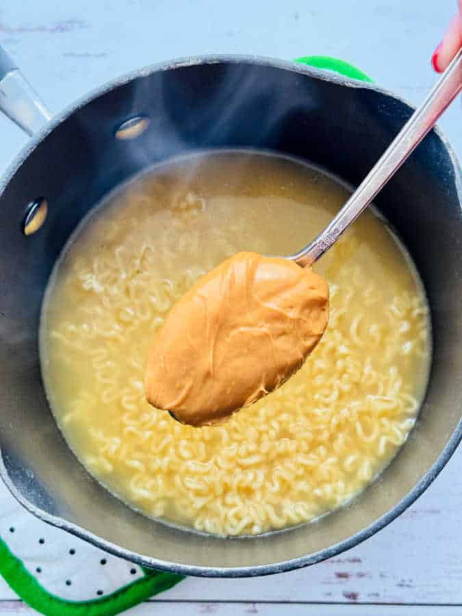 getting ready to stir a big spoonful of peanut butter into a hot pan of ramen noodles