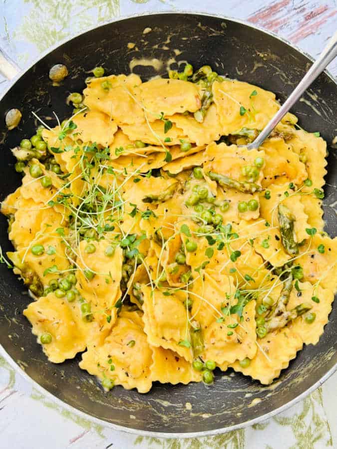 a pan full of ravioli primavera with a spoon, ready to serve