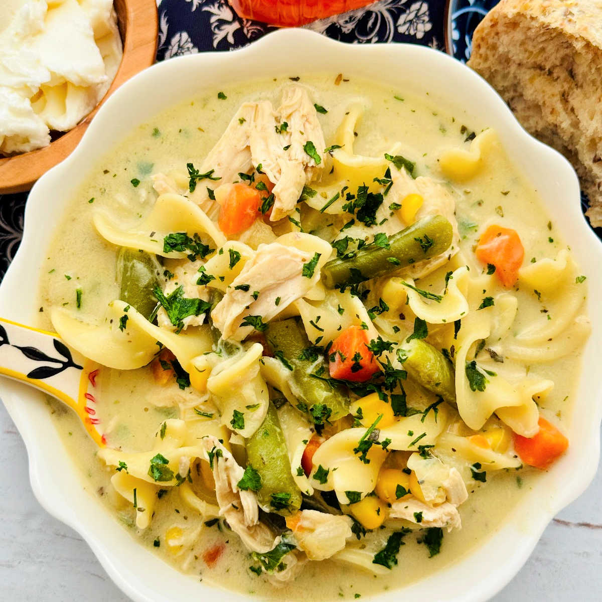 a white bowl filled to the brim with creamy rotisserie chicken noodle soup